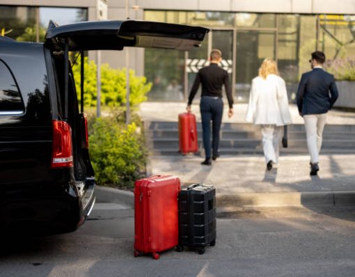 Driver or concierge helps a business couple carry their suitcases to the office or hotel from a minivan taxi. Concept of business travel and transportation service
